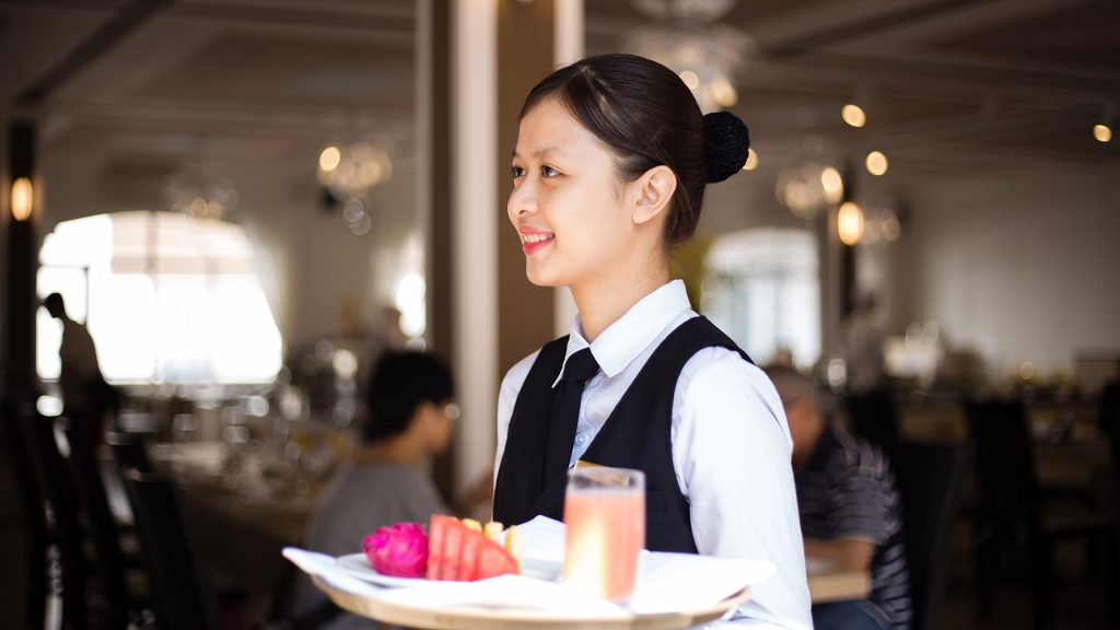 Nhân viên phục vụ F&B mang món tới bàn khách